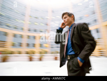 Imprenditore parlando al cellulare, esterno, edificio di sfondo sfocato. Foto Stock