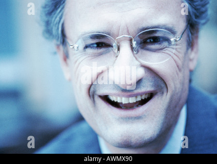 Imprenditore con gli occhiali, sorridente in telecamera, close-up Foto Stock