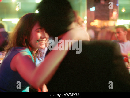Giovane uomo e donna che parlano in bar, donna con la mano intorno all uomo il collo Foto Stock
