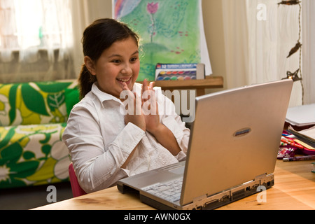 Giovani schoolgirl lavora con il computer portatile, godendo di se stessa Foto Stock