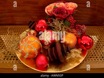 Ornato Ornamenti natale e rose artificiali seduto su di una piastra d'oro Foto Stock