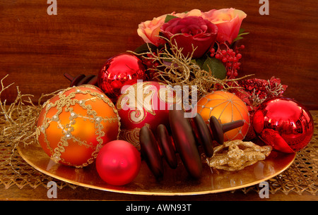 Ornato Ornamenti natale e rose artificiali seduto su di una piastra d'oro Foto Stock