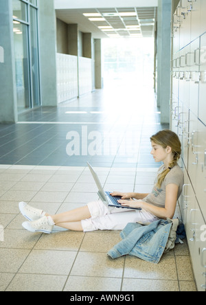 High School girl utilizzando laptop nel corridoio della scuola Foto Stock