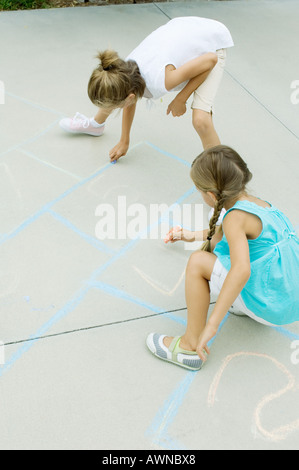 Ragazze disegno campana gioco sul viale di accesso Foto Stock