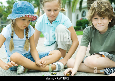 Bambini che giocano marmi in strada residenziale Foto Stock