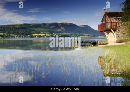 Alba sull'Ullswater, vicino Pooley Bridge. Ancora acqua con riflessioni e canne su un blu brillante mattinata estiva nel Lake District Cumbria Foto Stock