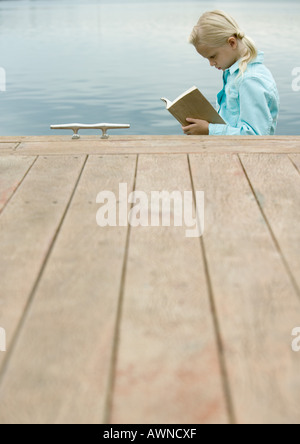 Lettura della ragazza prenota da acqua Foto Stock