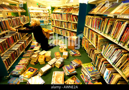 Una donna ordinamento bibliotecario libri per bambini per ispirare a energia solare Nuova libreria Foto Stock