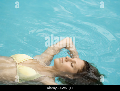 Donna galleggiante sul retro in piscina Foto Stock