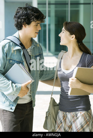 Coppia giovane sul campus universitario, sorridente ad ogni altro Foto Stock