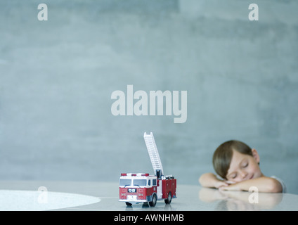 Ragazzo con gli occhi chiusi, giocattolo motore Fire in primo piano Foto Stock