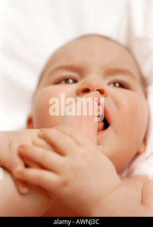 Il Bambino giacente sul retro, mettendo piede in bocca, close-up. Foto Stock