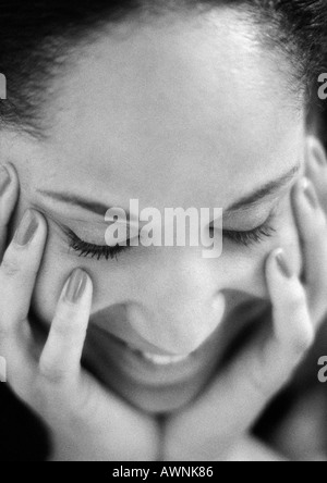 Donna che mantiene il viso con le mani e gli occhi chiusi, close-up, B&W. Foto Stock