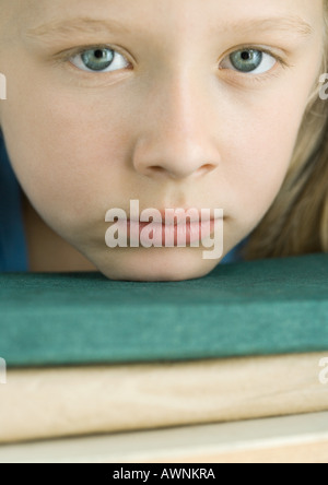 Ragazza mento di appoggio sulla pila di libri Foto Stock
