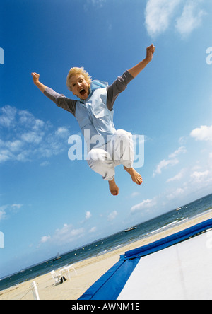 Donna matura di saltare sul trampolino presso la spiaggia Foto Stock