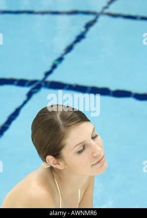 Donna vicino alla piscina a occhi chiusi e sorridente Foto Stock