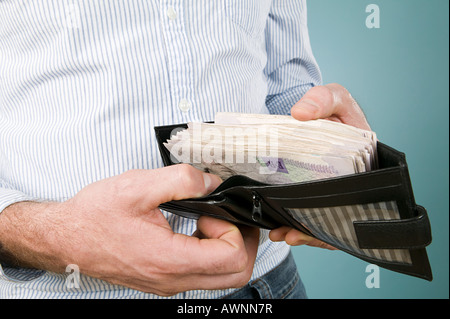 Uomo con delle banconote in euro nel suo portafogli Foto Stock