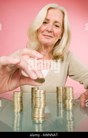 Donna di monete di impilamento Foto Stock