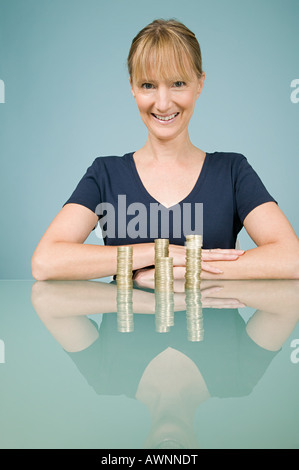 Donna con pile di monete Foto Stock