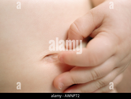 Baby toccando navel, close-up Foto Stock