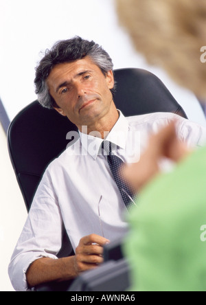 Imprenditore alla scrivania, ascoltando la donna in primo piano sfocato Foto Stock