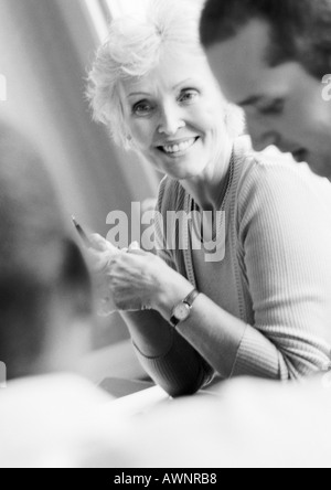 Imprenditrice matura in conferenza, sorridente, con due colleghi, B&W Foto Stock