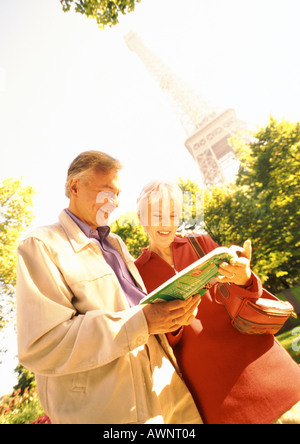 Francia, Parigi, donna matura e uomo esaminando un libro, Torre Eiffel in background Foto Stock