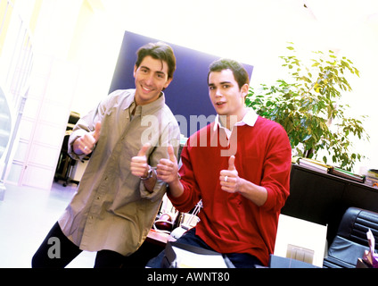 Due uomini in office dando Thumbs up, guardando la telecamera, ritratto Foto Stock