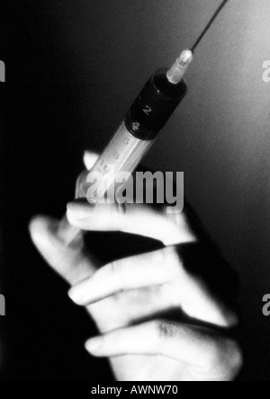 Mano che tiene la siringa, close-up, B&W Foto Stock