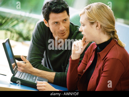 Uomo e donna che parlano e utilizzando il computer portatile Foto Stock