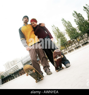 Giovane uomo e donna in piedi insieme con skateboard, ritratto Foto Stock