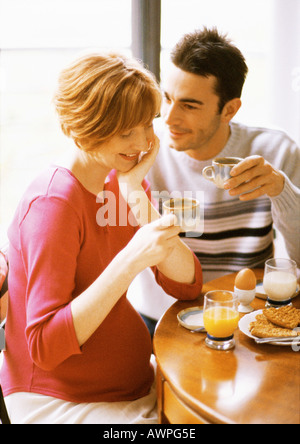 Donna incinta e uomo avente la colazione, sorridente Foto Stock