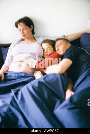 Donna incinta, uomo e bambino a letto insieme Foto Stock