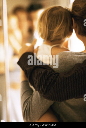 Bracci holding bambino, vista posteriore, offuscata Foto Stock