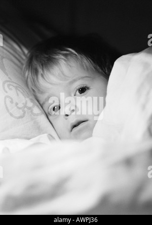 Piccola ragazza nel letto sotto una coperta di close-up, b&W Foto Stock