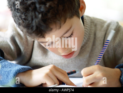 Ragazzo testa di piegatura su notebook, la scrittura, close-up Foto Stock