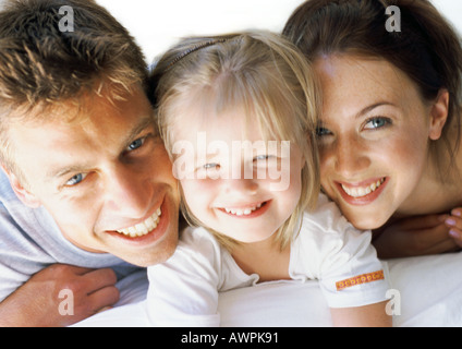 Bambina che giace tra i genitori, sorridente, close-up Foto Stock