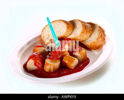 Salsiccia al curry, affettata con ketchup e fette di pane su un piatto di carta Foto Stock