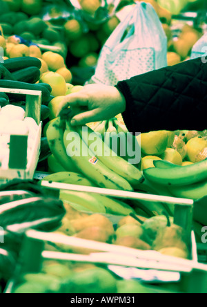 Mano scegliendo le banane tra produrre, close-up Foto Stock