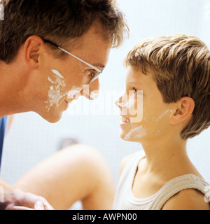 Padre e Figlio con crema di rasatura su facce, vista laterale Foto Stock