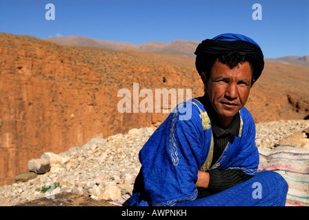 Vestito marocchino in blu seduto di fronte a rocce rosse, Dades Gorge, Quarzazate, Marocco, Africa del Nord Foto Stock