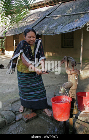 BANGLADESH donna dei tribali Garo minoranza ottenere acqua dalla sua pompa a mano Foto Stock