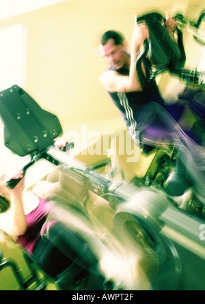 L uomo e la donna con cyclette in palestra, movimento sfocato Foto Stock