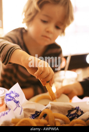 Bambino mangiare anelli di cipolla, offuscata, ritratto. Foto Stock