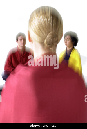 Gente seduta sul pavimento, meditando, offuscata Foto Stock