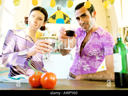 Matura in piedi in cucina, aumentando la loro bicchieri. Foto Stock