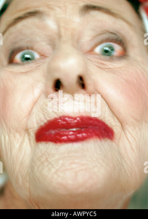 Senior donna che indossa un rossetto rosso guardando la telecamera, ritratto, extreme close-up Foto Stock