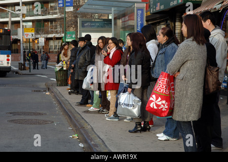 In attesa per il bus su Broadway multi culturale Elmhurst Queens quartiere in NYC Foto Stock