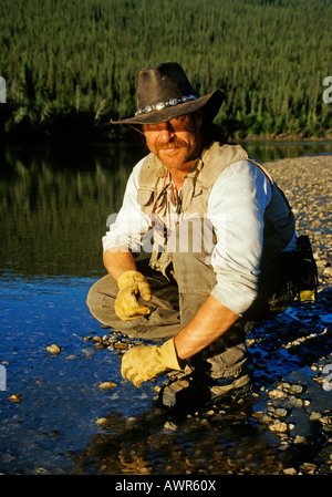 L'uomo accovacciato al bordo del fiume, Brooks Range, Alaska Foto Stock