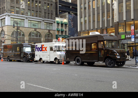 Carrelli UPS circondano un FedEx carrello parcheggiato nel centro di indumento in NYC Foto Stock